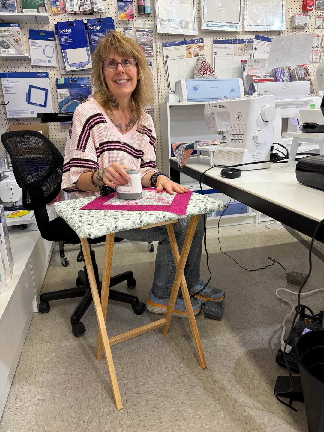 A woman sitting in front of a small iron table/pressing table to promote a class to make a pressing table. 