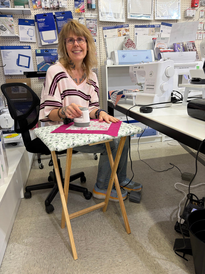 A woman sitting in front of a small iron table/pressing table to promote a class to make a pressing table. 